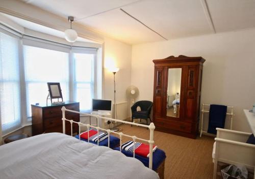 a bedroom with a bed and a desk and a mirror at Captains Cottage in Deal