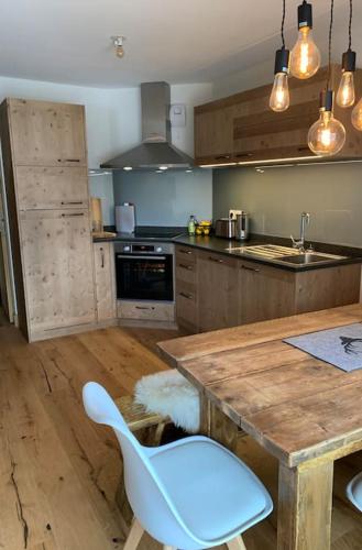 - une cuisine avec une table en bois et une chaise blanche dans l'établissement Pom Pom, 3 bedroom apt with stunning mountain views-Samoëns, à Samoëns