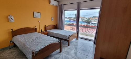sypialnia z 2 łóżkami i dużym oknem w obiekcie Residencial Lareira do Pinheirinho w mieście Almada