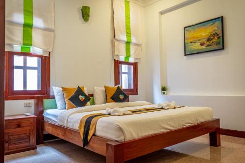 a bedroom with a bed with yellow and green accents at Antonios Villa Hotel in Siem Reap