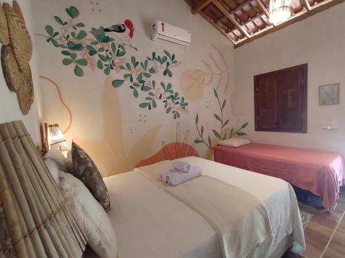 a bedroom with two beds and a wall with a flower mural at Pousada Quintal dos Sonhos Xandó Caraiva in Caraíva