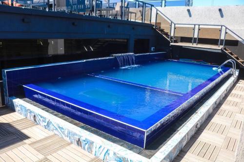 uma grande piscina azul no topo de um edifício em Bello Monoambiente ZV212, Edif Zetta Village Airport em Colonia Mariano Roque Alonso