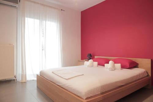 - une chambre avec un grand lit et un mur rouge dans l'établissement 5 min from Papageorgiou Free Indoor Parking, à Thessalonique