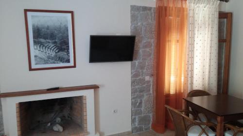 a living room with a fireplace and a television at Mouria Pension Rooms & Studios in Ancient Epidavros