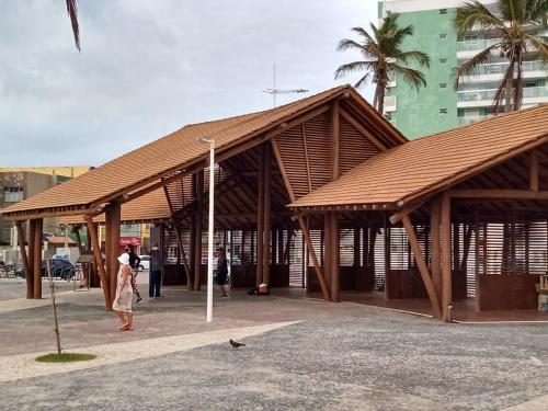 um pavilhão de madeira com pessoas andando em frente a um edifício em Loft Pituba Sol em Salvador