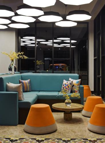 a lobby with a blue couch and orange chairs at Zone By The Park Coimbatore in Coimbatore