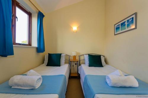 two beds in a room with blue curtains at CROYDE DUNE LODGE 3 Bedrooms in Croyde