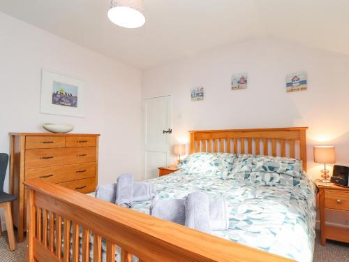 a bedroom with a wooden bed and a wooden dresser at By-sea in Marazion