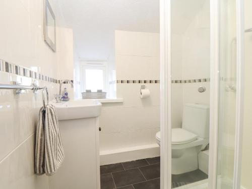 a white bathroom with a toilet and a sink at By-sea in Marazion