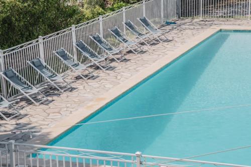 an empty swimming pool with chairs and a fence at Hôtel Castel Saint Anne in Le Castellet