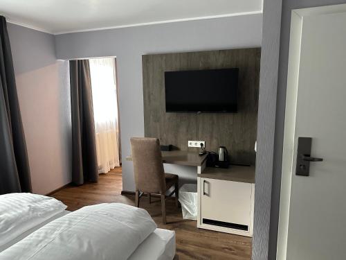 a hotel room with a desk and a television on a wall at Hotel Restaurant Mirena in Marl