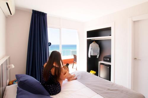 a woman sitting on a bed in a bedroom at Ibersol Sorra d'Or in Malgrat de Mar