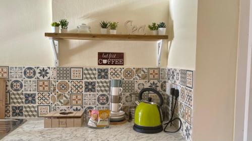 a kitchen counter with a green tea kettle on a tile wall at ORCHARD HILL HOUSE Apartment in Paignton