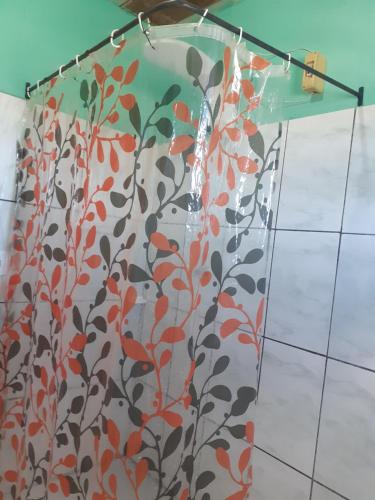 cortina de ducha con estampado de flores naranja y negra en Casa Pôr do Sol, en São Thomé das Letras
