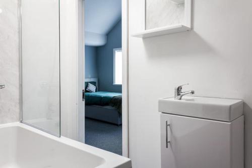 ein Bad mit einem Waschbecken und einem Spiegel in der Unterkunft Modern 5 Bed Near LFC Stadium in Liverpool