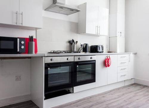 eine Küche mit weißen Schränken und einem schwarzen Backofen in der Unterkunft Modern 5 Bed Near LFC Stadium in Liverpool