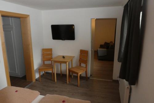 a room with a table and chairs and a television on the wall at Pension Mühle in Zell am See
