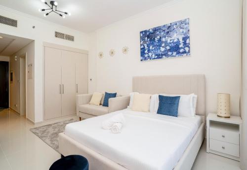 a white bedroom with a large white bed and a couch at Tanin - Studios at Damac Hills Carson Tower C in Dubai