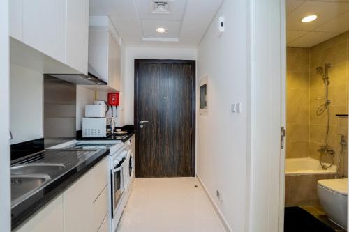 a kitchen with a sink and a wooden door at Tanin - Studios at Damac Hills Carson Tower C in Dubai