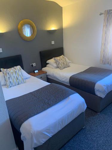 a hotel room with two beds and a mirror at Abbots Mead Hotel in Shrewsbury