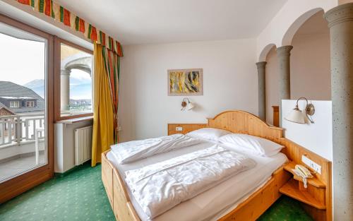 a bedroom with a bed and a large window at Hotel Reipertingerhof in Brunico