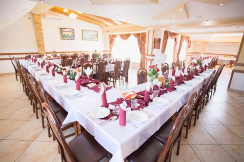 a long table in a room with tables and chairs at Penzión Kolkáreň in Stará Ľubovňa