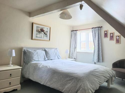 a bedroom with a white bed and a window at Two Bed First Floor Apartment in Village location in Grantham