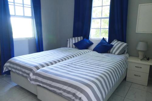 Schlafzimmer mit einem großen Bett und blauen Vorhängen in der Unterkunft Resident Emiterio in Blue Bay