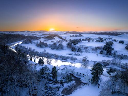 an aerial view of a snow covered field with the sunset at Maryculter House in Maryculter