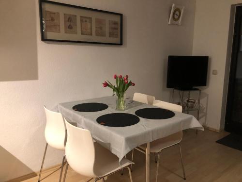 a table with white chairs and a vase of flowers on it at Ferienwohnung Nationalpark Eifel Nideggen Sauna in Nideggen
