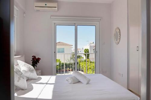 a bedroom with two white beds and a large window at Velomar Villa in Paralimni