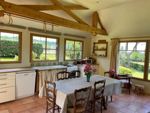 eine Küche mit einem Tisch mit Stühlen und eine Küche mit Fenstern in der Unterkunft Le colombier, villa vue mer accès plage 300M in Varengeville-sur-Mer