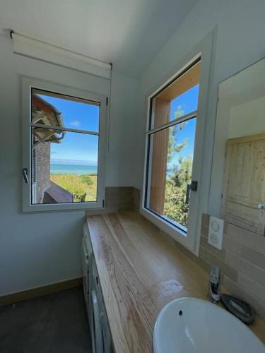 une salle de bain avec un lavabo et deux fenêtres dans l'établissement Le colombier, villa vue mer accès plage 300M, à Varengeville-sur-Mer