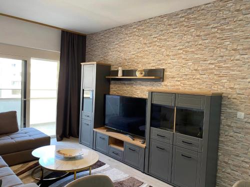 a living room with a television and a brick wall at Ulcinj Apartments in Ulcinj
