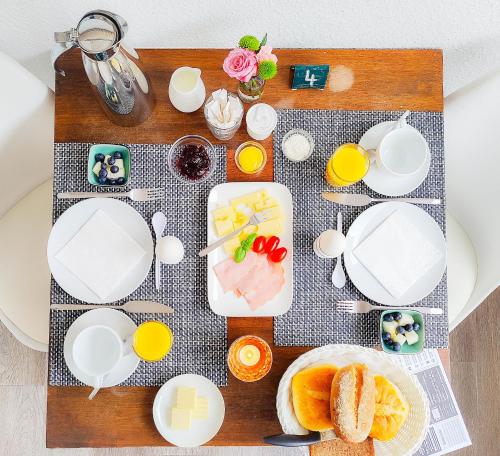 uma mesa coberta com pratos brancos e tigelas de comida em Haus Menno Janssen - Doppelzimmer em Norderney