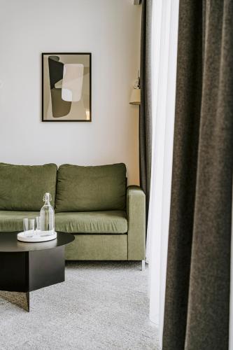 a living room with a green couch and a table at Poziom 511 Jura Wellness Hotel & Spa in Ogrodzieniec
