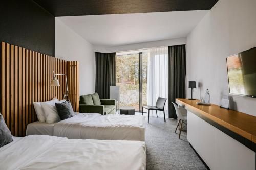 a hotel room with two beds and a desk at Poziom 511 Jura Wellness Hotel & Spa in Ogrodzieniec
