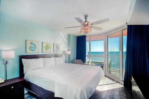 a bedroom with a bed with a ceiling fan and a balcony at Prince Resort Oceanfront 1834 at Cherry Grove Pier in Myrtle Beach