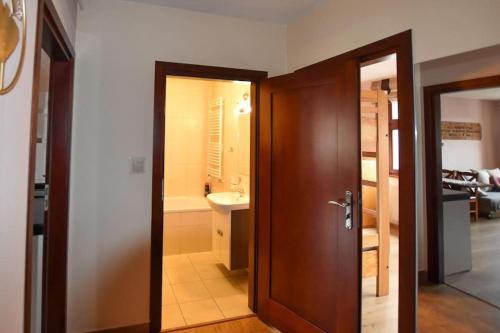 ein Bad mit einer Tür, die sich zu einem Badezimmer mit einem Waschbecken öffnet in der Unterkunft APARTAMENTY TR 11 Apartament nr 6 in Olsztyn