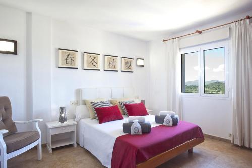 a bedroom with a bed and a chair and a window at Villa Heura 18 in Alcudia