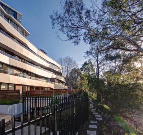 a fence in front of a building with trees at Eden Condo Abbotsford in Melbourne