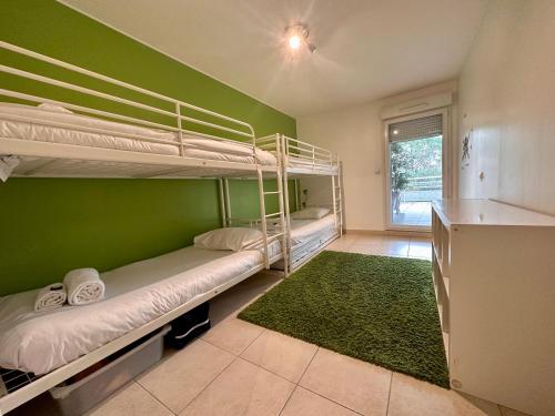 Cette chambre comprend 2 lits superposés et un mur vert. dans l'établissement PGH N6 - 100m de la Plage, Terrasse, Parking, à La Grande Motte