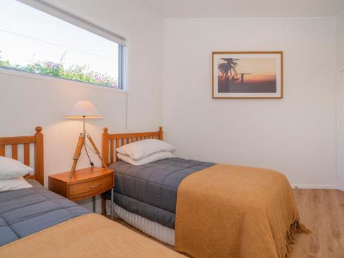 a bedroom with two beds and a window at Coast Awhile - Whangamata Holiday Home in Whangamata