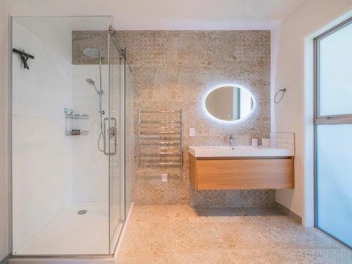 La salle de bains est pourvue d'une douche, d'un lavabo et d'un miroir. dans l'établissement Coast Awhile - Whangamata Holiday Home, à Whangamata
