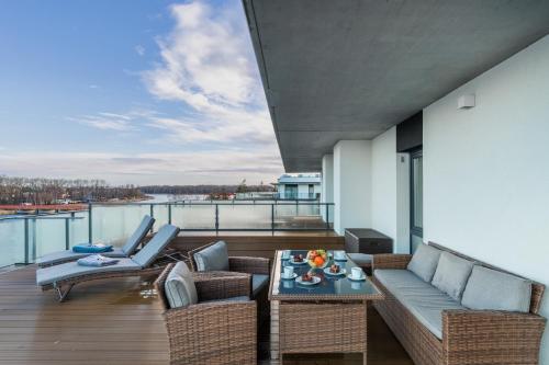 a balcony with a couch and chairs and a table at Wellness & SPA Resort Dziwnów Apartments with Parking by Renters Prestige in Dziwnów