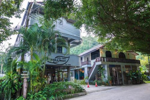 un edificio con una palmera delante de él en THANSILA Resort, en Ranong
