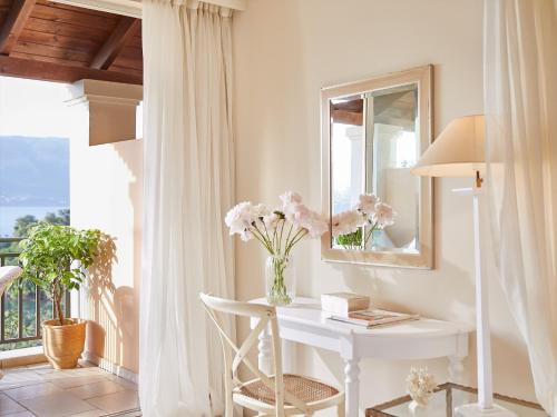 a white desk with a vase of flowers on a balcony at Grecotel Eva Palace in Kommeno