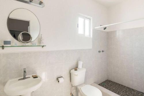 een badkamer met een toilet, een wastafel en een spiegel bij Casa MiAmore - Family Getaway in Cancun