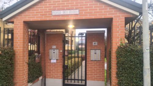 a red brick building with a black gate at B&B- La Casa Blu- Forum di Assago, Humanitas, Milanofiori, IEO in Rozzano