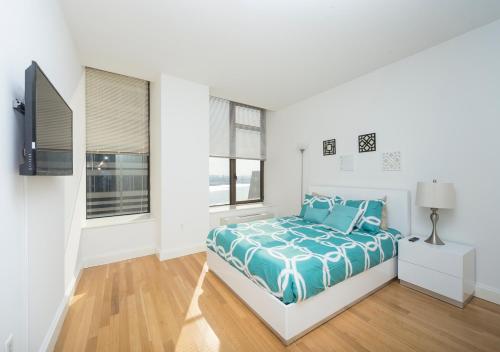 a white bedroom with a bed with a blue comforter at Fantastic 3BR At Financial District in New York